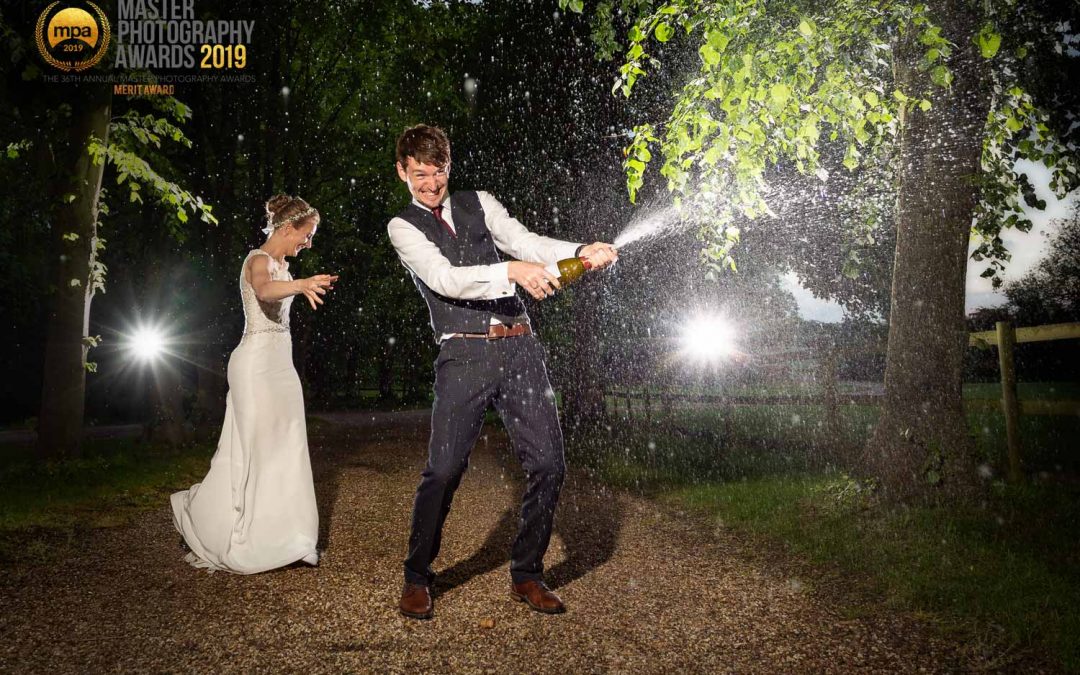 Newly married couple spraying champagne on their wedding day at Colville Hall in Essex
