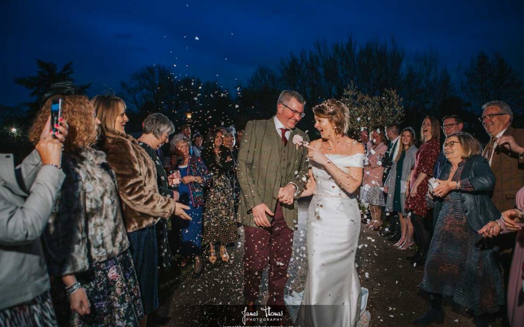 Bride and groom walking at night while guests throw confetti at The White Hart in Great Yeldham.