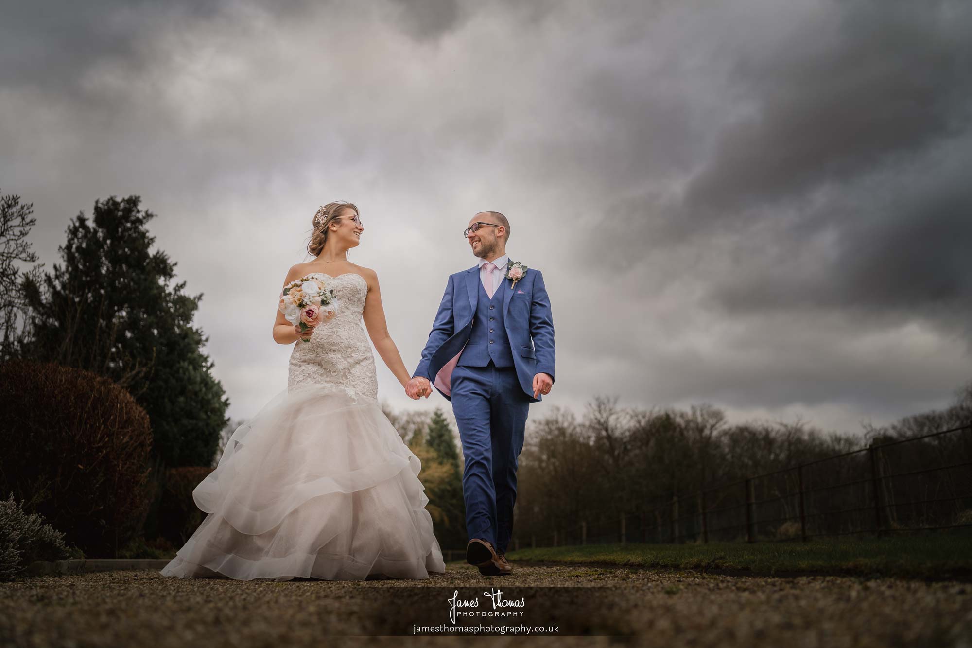 Married couple holding hands and walking at Gaynes Park Wedding Venue